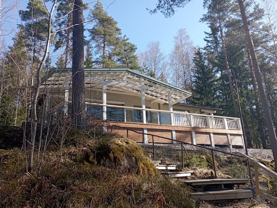 Loma-asunnon lasikaiteinen terassilaajennus metsässä