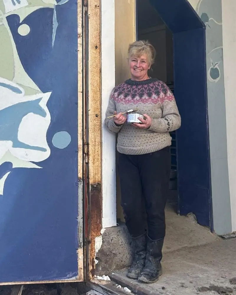 Architect Kirsi Komulainen in front of a cat mural she painted herself