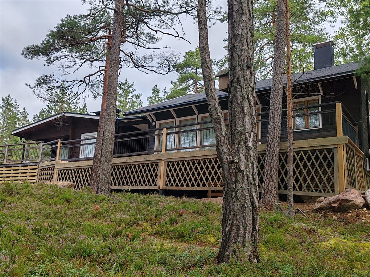 Tumma loma-asunto männikössä, uusi terassi ristikkosäleiköin verhoiltuine sokkeleineen