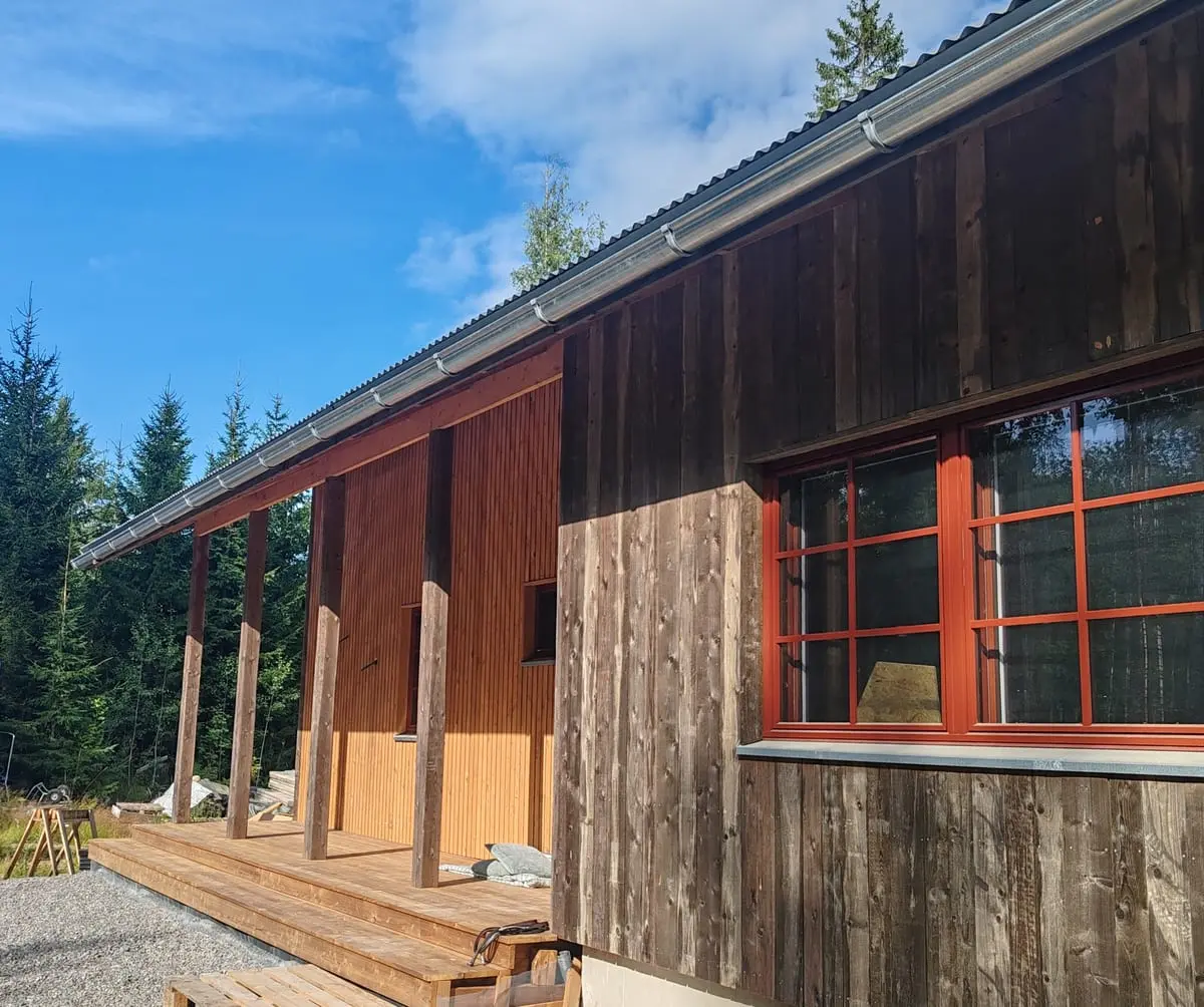 Latotalon julkisivu katetulta terassilta, punaruskeat ikkunanpuitteet