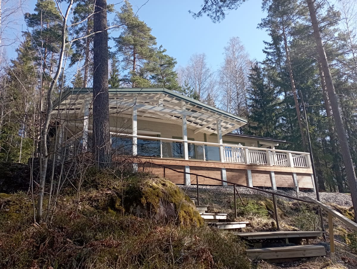 Vaalea loma-asunto rinteessä, katettu terassi ja kiviportaat