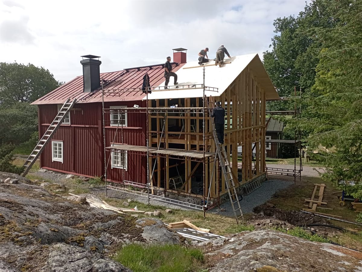 Laajennuksen runko nousee päädyssä, kirvesmiehet kattotöissä