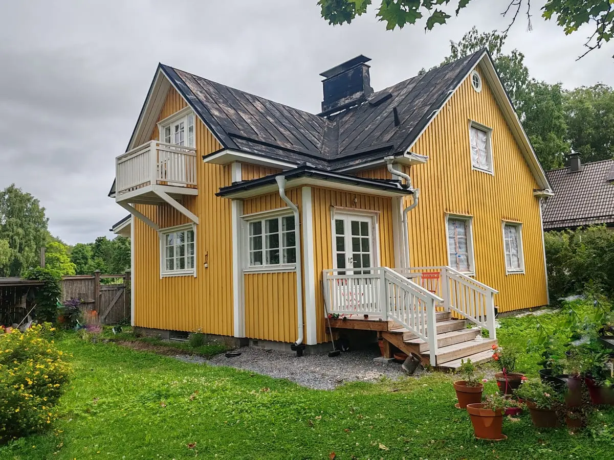 Keltainen talo pihan puolelta: parveke, kuisti ja uudet portaat