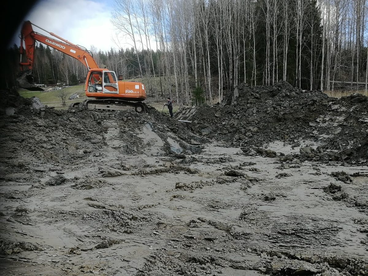 Kaivinkone kaivaa tekolampea saunan pihapiiriin